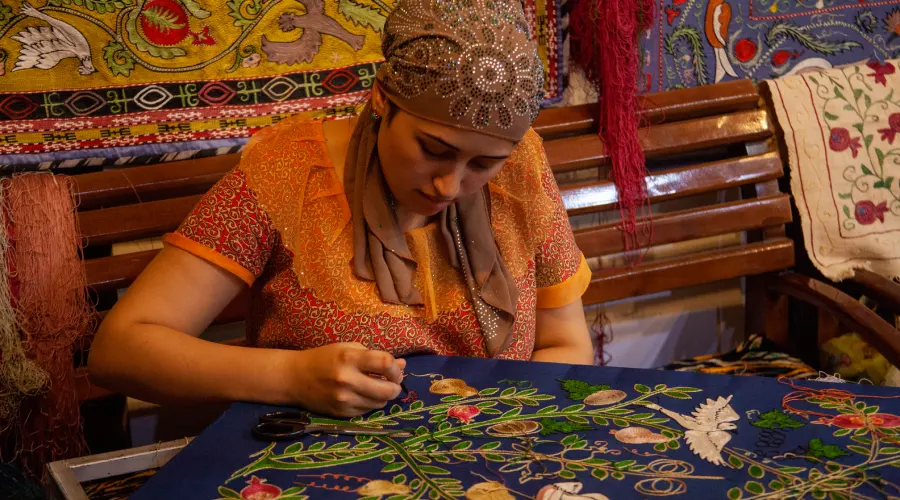 Kashmiri artisan hand-embroidering traditional fabric with colorful floral patterns