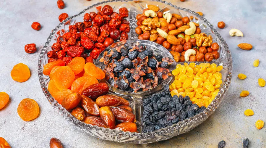 Assorted Kashmiri dry fruits including almonds, walnuts, raisins, apricots, and dates in a serving tray.