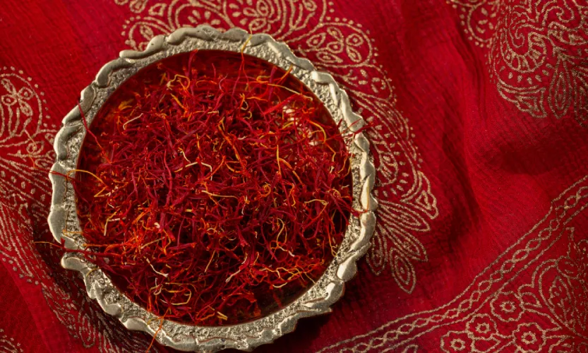 Premium Kashmiri saffron threads in a silver bowl on red traditional fabric