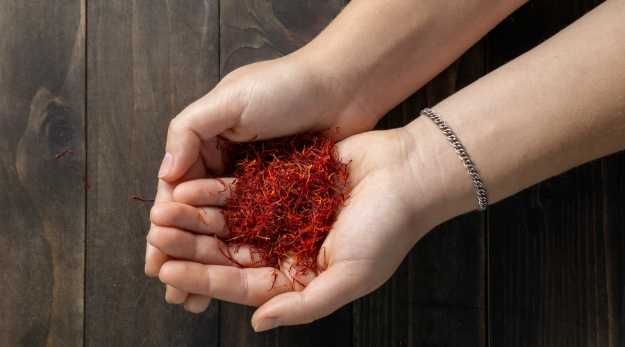 Hands holding premium Kashmiri saffron threads over wooden background